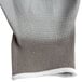 A close up of a gray and white nylon glove with gray palm coating.