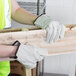 A person wearing Cordova standard grain cowhide driver's gloves holding a piece of wood.