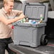 A man opening a CaterGator outdoor cooler filled with green bottles.