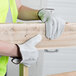 A person wearing small Cordova grain cowhide leather driver's gloves holding a piece of wood.