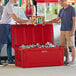 Two men standing next to a red CaterGator outdoor cooler full of cans.