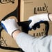 A man wearing Cordova blue latex palm coated gloves holding a box.