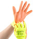 A hand wearing a Cordova hi-vis yellow glove with hi-vis orange palm coating.