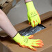 A person wearing Cordova Hi-Vis yellow gloves with orange palm coating opening a box.