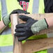 A pair of small gloved hands holding a piece of wood.