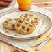 A plate with two Swapples Vegan Everything Waffles and a glass of orange juice.