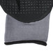A close up of a small Cordova Conquest Max black and grey warehouse glove with nitrile dots and hand coating.