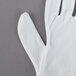 A Cordova white nylon inspection glove on a gray surface.