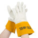 A pair of hands wearing yellow welding gloves with russet cuffs.