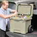 A man putting bottles in a CaterGator tan outdoor cooler.