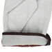 A pair of white leather Cordova driver's gloves with brown fabric on the back.