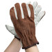 A pair of Cordova cowhide driver's gloves with brown split leather backs on a person's hands.