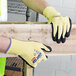 A person wearing black and yellow Cordova ActivGrip Advance Kevlar gloves holding a piece of wood.