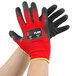 A pair of hands wearing red and black Cordova iON Flex gloves with dark gray latex palm coating.