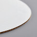 A close up of a white Baker's Mark corrugated cake circle.