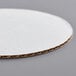 A Baker's Mark white corrugated cake circle with a brown surface.