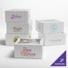 A group of white Baker's Lane bakery boxes with a blue and purple logo on them.