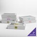 A stack of white Baker's Lane boxes with purple and yellow designs.