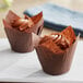 Two chocolate cupcakes in Baker's Mark tulip baking cups with brown frosting swirls.