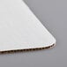 A close up of a white Baker's Mark corrugated cake pad.