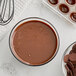 A bowl of brown liquid chocolate with a whisk next to a bowl of chocolate chips.