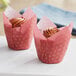Two cupcakes in red and gold tulip baking cup wrappers with frosting.