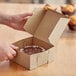 A person opening a Baker's Mark Kraft pie and bakery box on a counter.