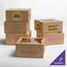 A group of Baker's Lane cardboard bakery boxes with cut out windows on a table with different logos on them.