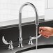 A hand opening a Delta deck-mount lavatory faucet with dual blade handles.