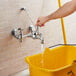 A person using a Delta mop sink faucet with yellow bucket.