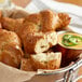 A basket of SuperPretzel Jalapeno Cheese Filled Soft Pretzel Knots with a cup of soup on a table.