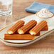 Bavarian cream filled mini churros on a plate with whipped cream and water.