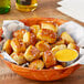 A bowl of J & J Snack Foods SuperPretzel Bavarian Soft Pretzel Bites with mustard and cheese sauce.