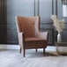 A Flash Furniture brown faux leather wingback chair with wooden legs in a lounge area.