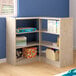 A Flash Furniture wooden corner shelf unit with books and boxes on the shelves.