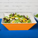 A Keywest sunset melamine bowl filled with salad on a table.