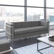 A Flash Furniture Hercules Regal gray leather sofa in a lounge area with a large window.