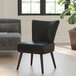 A Flash Furniture black leather accent chair with mahogany wood legs in a lounge area.