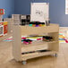 A wooden mobile storage cart with paint bottles and brushes on it.