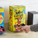 A hand reaching into a black box of Sour Patch Kids with different colored characters.