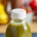 A white unlined tamper-evident cap on a bottle of green juice.