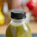 A Black Unlined Tamper-Evident cap on a bottle of green juice.