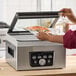 A person using a Galaxy vacuum packaging machine to seal a bag of food.