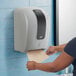 A woman using a Lavex WiFi-enabled automatic paper towel dispenser to get a paper towel.