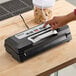 A person's hand pressing a button on a black and silver Galaxy vacuum sealer.