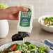 A person pouring Only Plant Based! Vegan Blue Cheese Dressing into a bowl of salad.