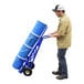 A man using a Vestil steel pail hand truck to move a blue steel pail.