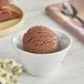 A bowl of chocolate ice cream with a scoop on a spoon.