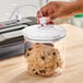 A hand opening a Galaxy vacuum canister of cookies on a kitchen counter.