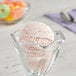 A bowl of strawberry ice cream with a scoop on top.